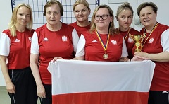 Polska reprezentacja w strojach reprezentacyjnych z medalami, pucharami i biało-czerwoną flagą